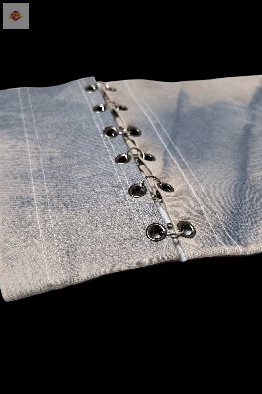 Détail des œillets et anneaux métalliques sur fond noir